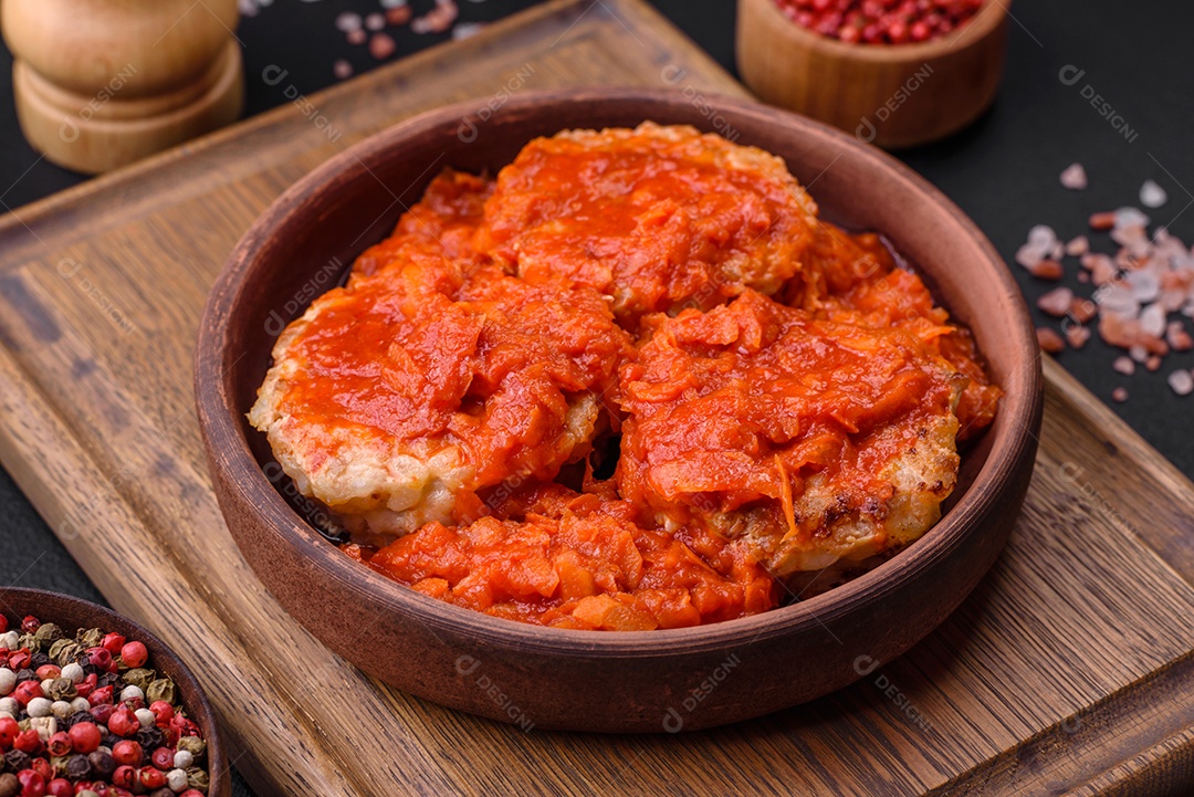 Deliciosas costeletas ou almôndegas frescas com especiarias, ervas e molho de tomate sobre um fundo escuro de concreto