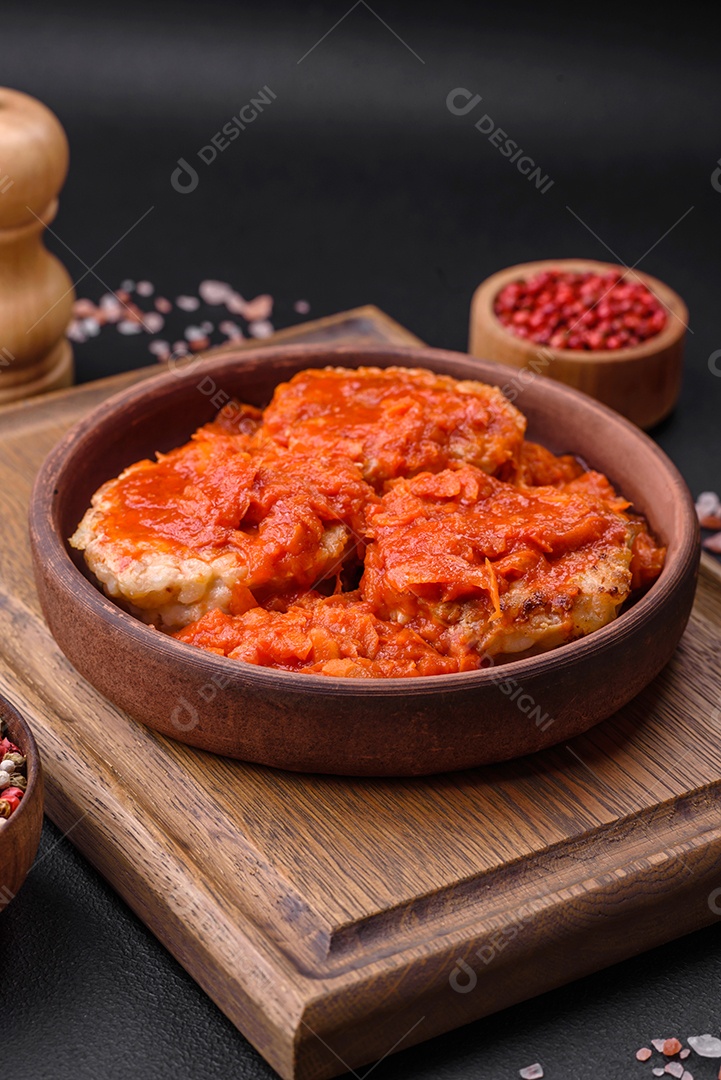 Deliciosas costeletas ou almôndegas frescas com especiarias, ervas e molho de tomate sobre um fundo escuro de concreto