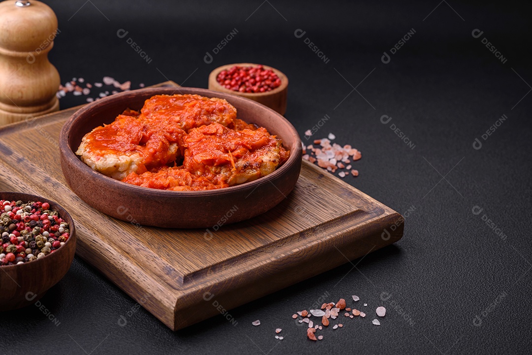 Deliciosas costeletas ou almôndegas frescas com especiarias, ervas e molho de tomate sobre um fundo escuro de concreto