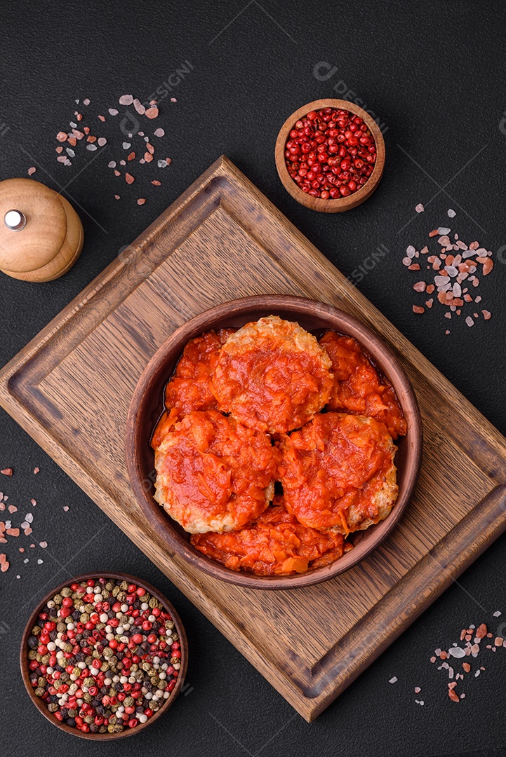 Deliciosas costeletas ou almôndegas frescas com especiarias, ervas e molho de tomate sobre um fundo escuro de concreto