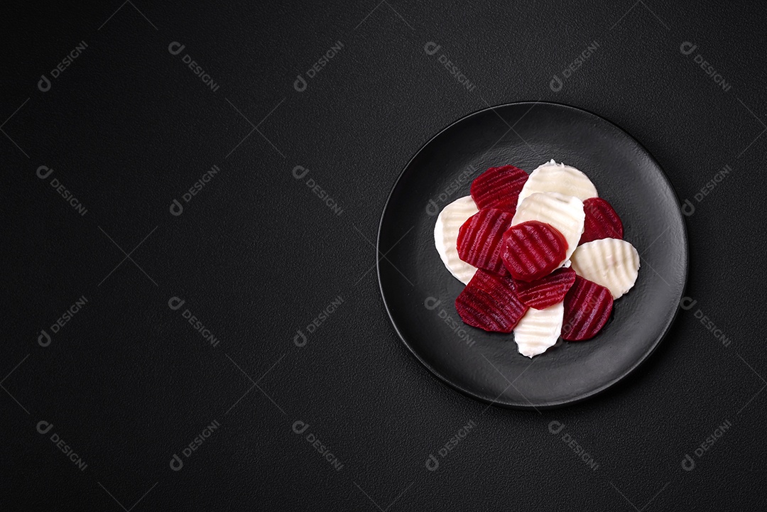 Deliciosa mussarela fresca e beterraba cozida cortada em fatias em uma placa cerâmica redonda sobre um fundo escuro de concreto
