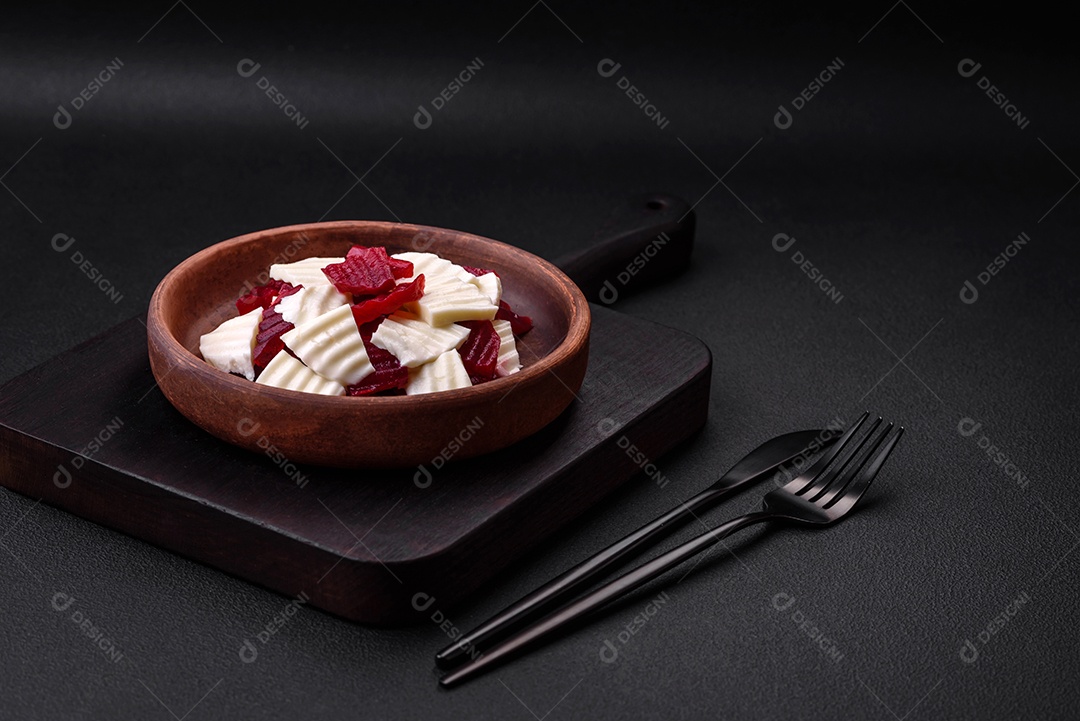 Deliciosa mussarela fresca e beterraba cozida cortada em fatias em uma placa cerâmica redonda sobre um fundo escuro de concreto