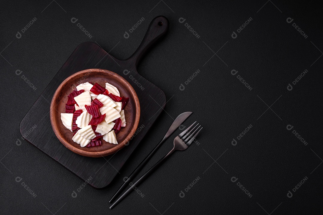 Deliciosa mussarela fresca e beterraba cozida cortada em fatias em uma placa cerâmica redonda sobre um fundo escuro de concreto
