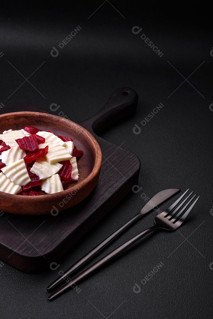 Deliciosa mussarela fresca e beterraba cozida cortada em fatias em uma placa cerâmica redonda sobre um fundo escuro de concreto
