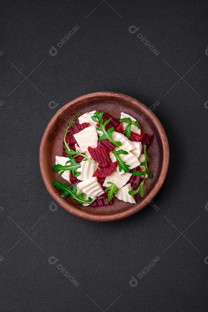 Deliciosa mussarela fresca e beterraba cozida cortada em fatias em uma placa cerâmica redonda sobre um fundo escuro de concreto