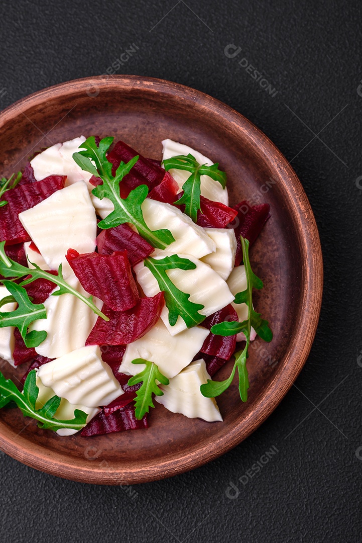 Deliciosa mussarela fresca e beterraba cozida cortada em fatias em uma placa cerâmica redonda sobre um fundo escuro de concreto