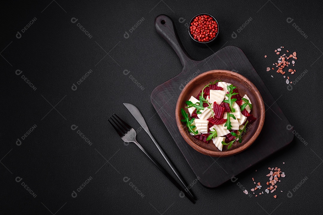 Deliciosa mussarela fresca e beterraba cozida cortada em fatias em uma placa cerâmica redonda sobre um fundo escuro de concreto