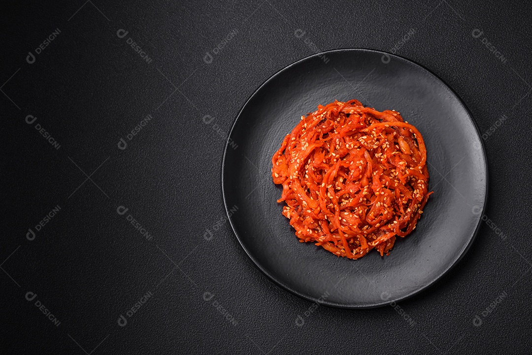 Lulas secas cortadas em fatias e temperadas com sementes de gergelim e especiarias sobre fundo escuro de concreto. Prato da culinária coreana