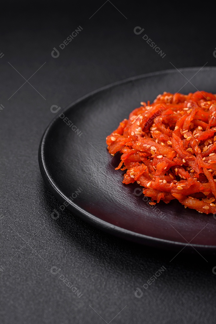 Lulas secas cortadas em fatias e temperadas com sementes de gergelim e especiarias sobre fundo escuro de concreto. Prato da culinária coreana