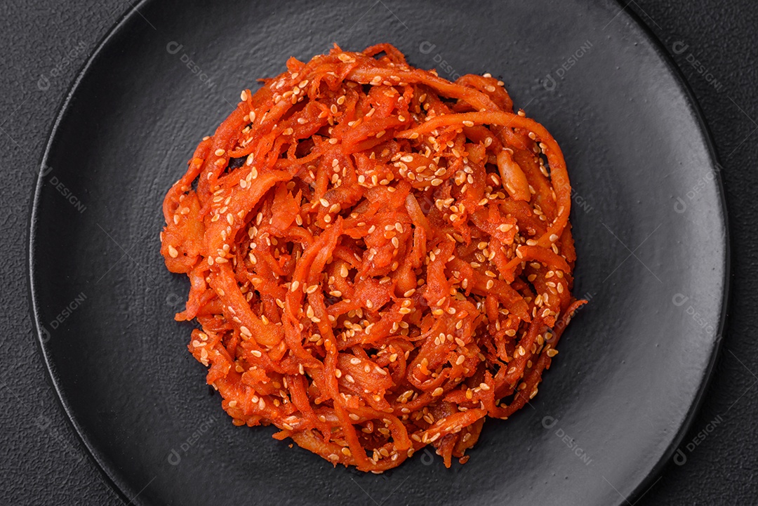 Lulas secas cortadas em fatias e temperadas com sementes de gergelim e especiarias sobre fundo escuro de concreto. Prato da culinária coreana