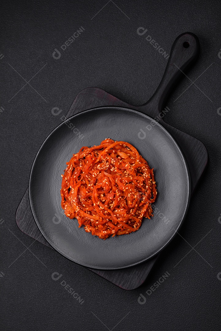 Lulas secas cortadas em fatias e temperadas com sementes de gergelim e especiarias sobre fundo escuro de concreto. Prato da culinária coreana