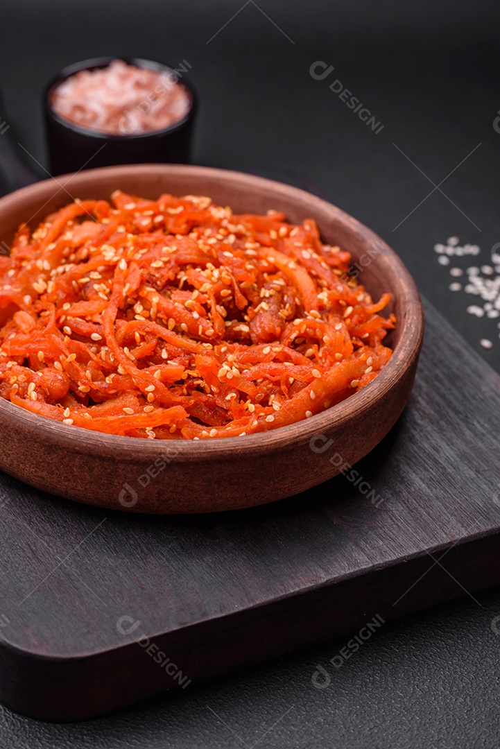 Lulas secas cortadas em fatias e temperadas com sementes de gergelim e especiarias sobre fundo escuro de concreto. Prato da culinária coreana