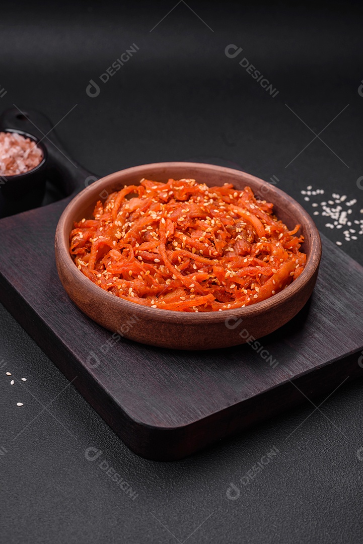 Lulas secas cortadas em fatias e temperadas com sementes de gergelim e especiarias sobre fundo escuro de concreto. Prato da culinária coreana