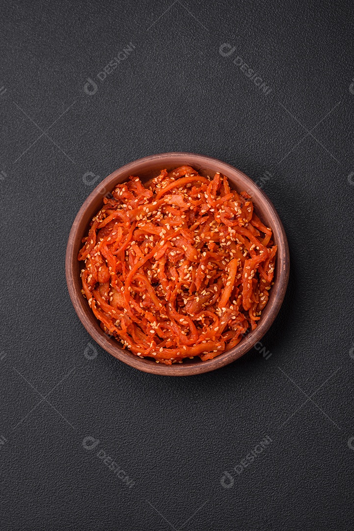 Lulas secas cortadas em fatias e temperadas com sementes de gergelim e especiarias sobre fundo escuro de concreto. Prato da culinária coreana