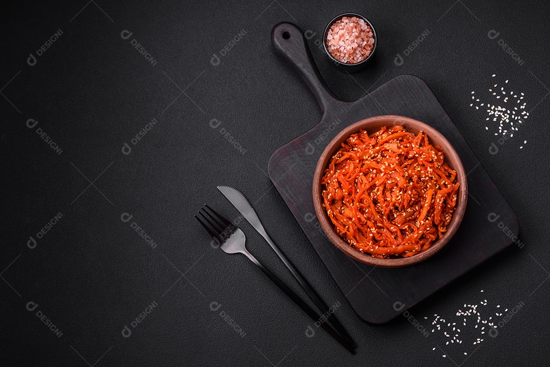 Lulas secas cortadas em fatias e temperadas com sementes de gergelim e especiarias sobre fundo escuro de concreto. Prato da culinária coreana