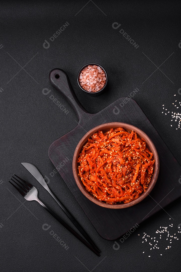 Lulas secas cortadas em fatias e temperadas com sementes de gergelim e especiarias sobre fundo escuro de concreto. Prato da culinária coreana