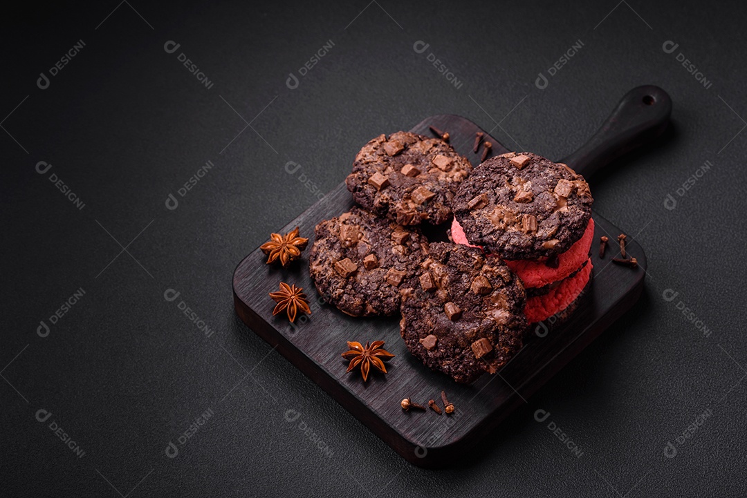 Deliciosos biscoitos de aveia crocantes e frescos com chocolate e nozes em uma placa de cerâmica preta sobre um fundo escuro de concreto