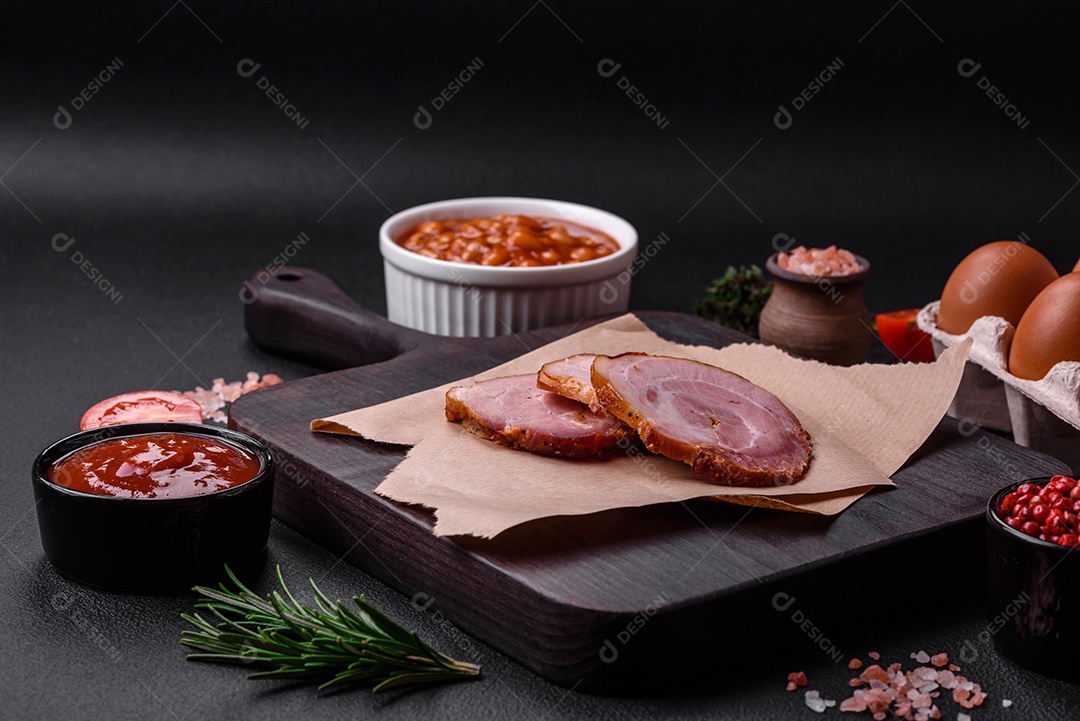 Delicioso café da manhã inglês nutritivo com ovos fritos, tomates, bacon e feijão em um fundo escuro de concreto
