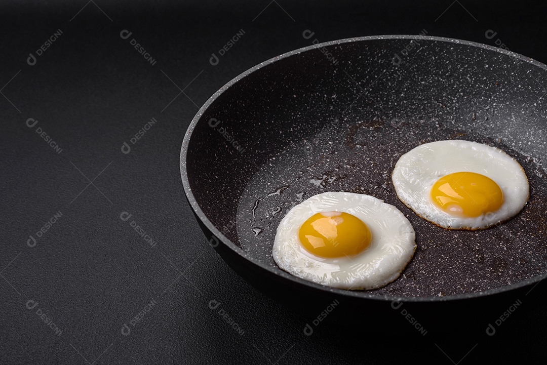 Delicioso ovos na frigideira em um fundo escuro de concreto.