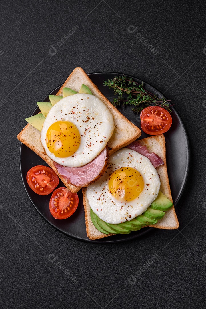 Delicioso café da manhã inglês nutritivo com ovos fritos, tomates, bacon e feijão em um fundo escuro de concreto