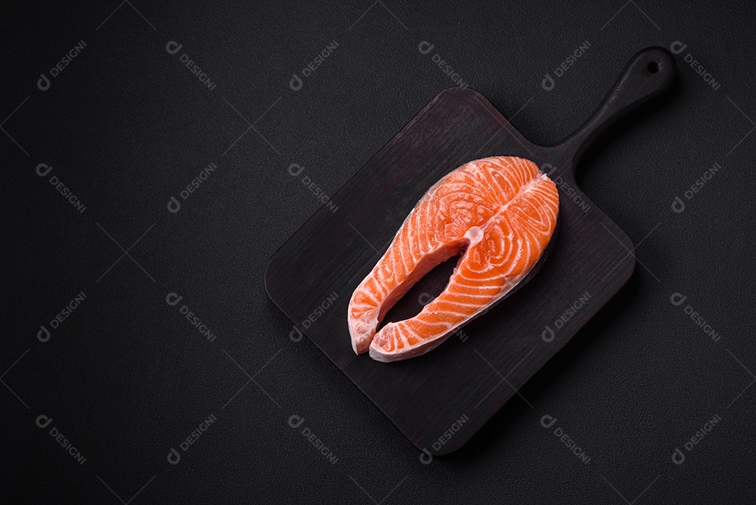 Bife de peixe vermelho cru fresco com especiarias e ervas sobre um fundo escuro de concreto