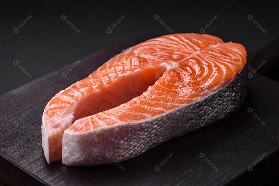 Bife de peixe vermelho cru fresco com especiarias e ervas sobre um fundo escuro de concreto