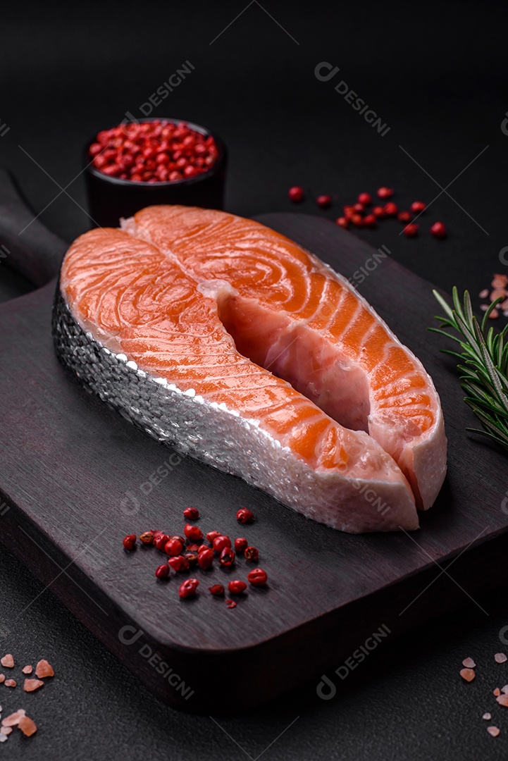 Bife de peixe vermelho cru fresco com especiarias e ervas sobre um fundo escuro de concreto