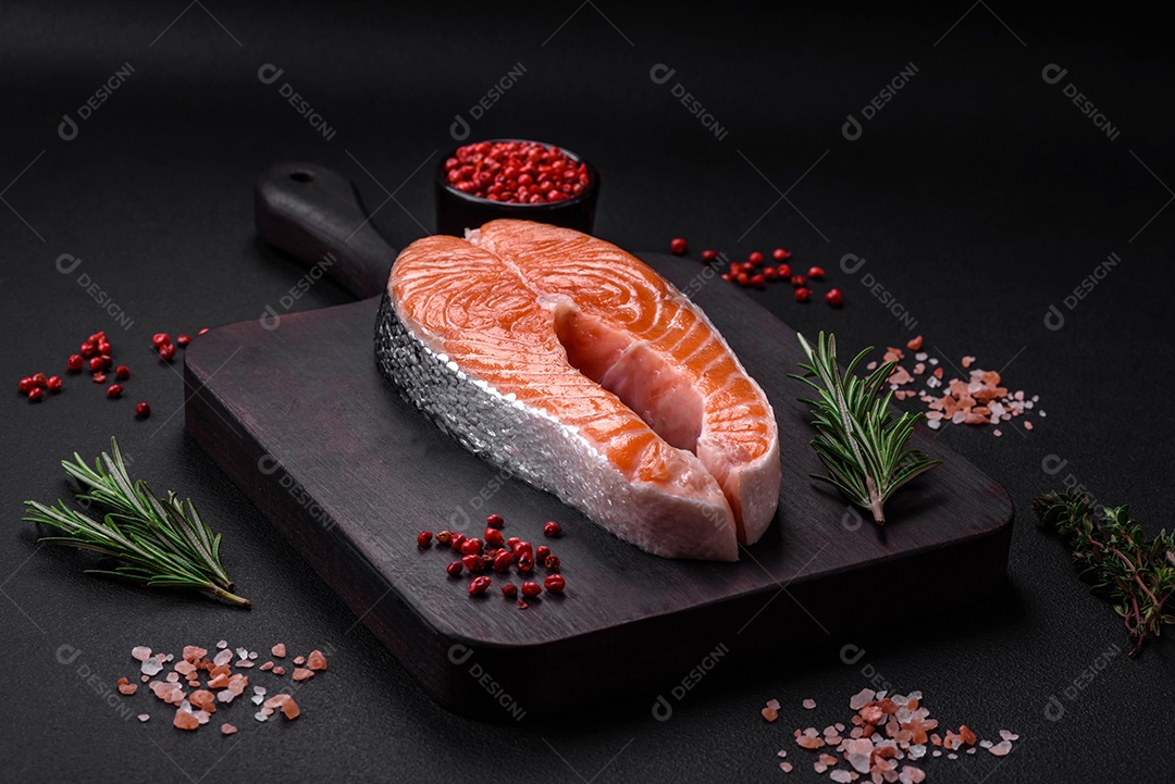 Bife de peixe vermelho cru fresco com especiarias e ervas sobre um fundo escuro de concreto