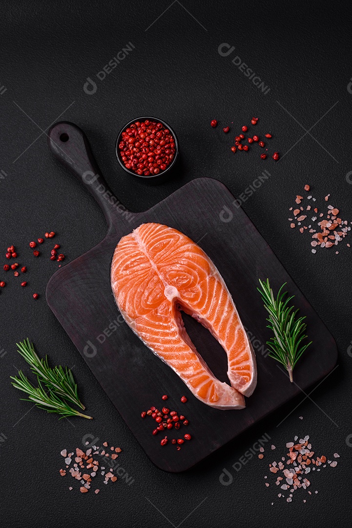 Bife de peixe vermelho cru fresco com especiarias e ervas sobre um fundo escuro de concreto