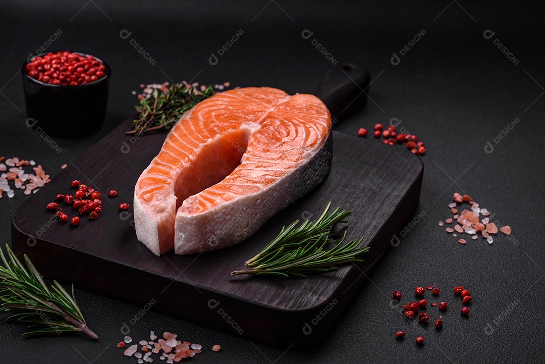 Bife de peixe vermelho cru fresco com especiarias e ervas sobre um fundo escuro de concreto