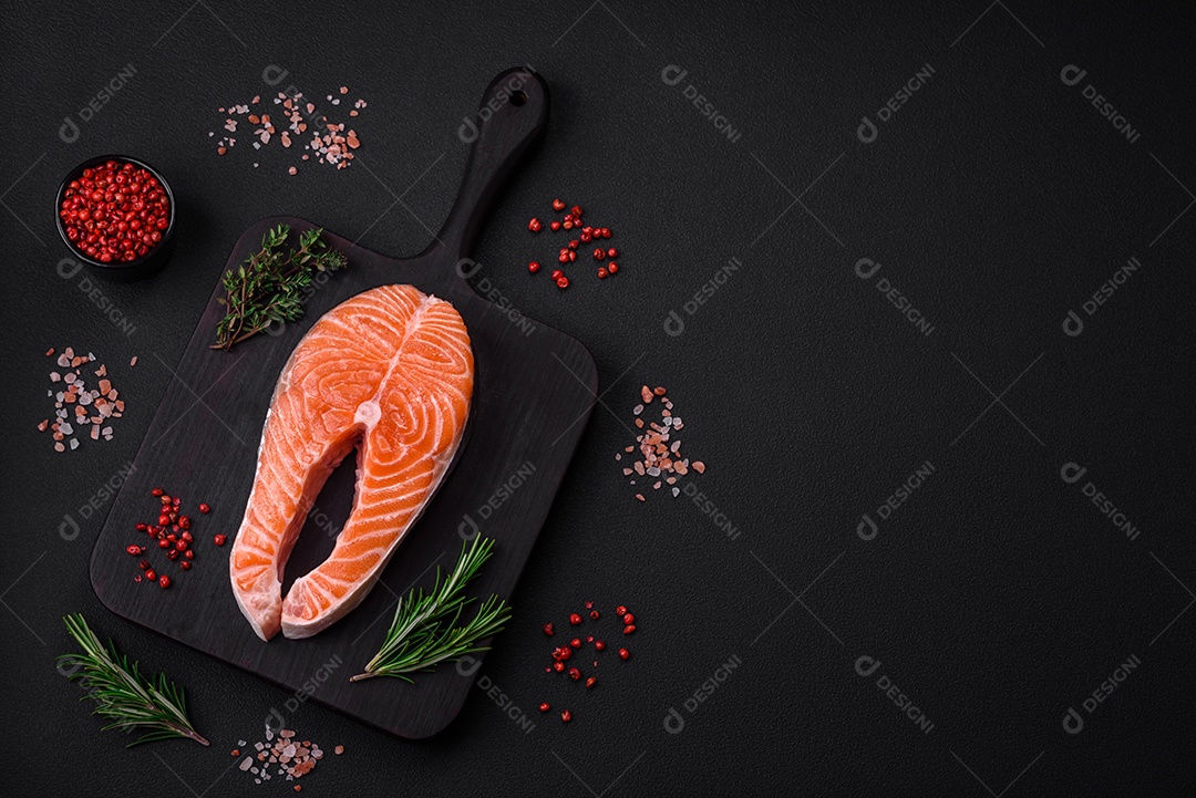 Bife de peixe vermelho cru fresco com especiarias e ervas sobre um fundo escuro de concreto