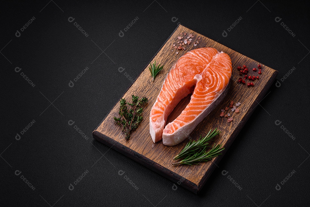 Bife de peixe vermelho cru fresco com especiarias e ervas sobre um fundo escuro de concreto