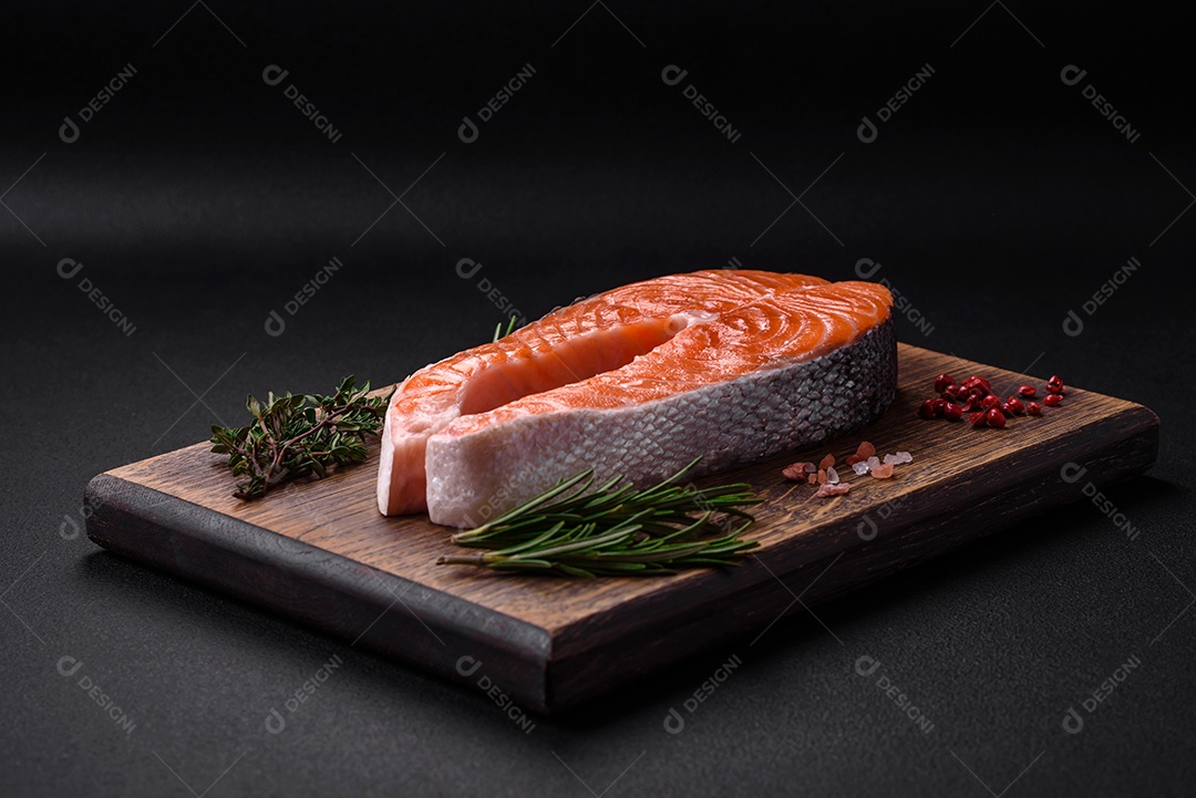 Bife de peixe vermelho cru fresco com especiarias e ervas sobre um fundo escuro de concreto