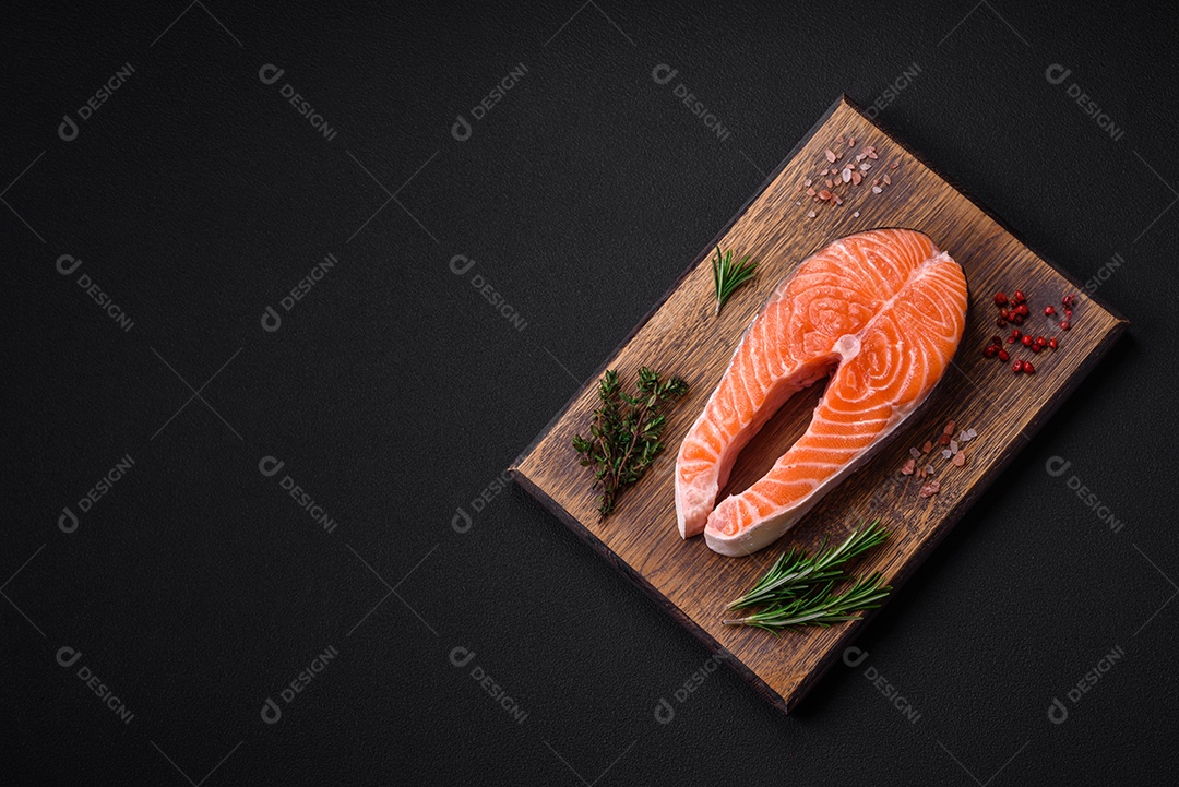 Bife de peixe vermelho cru fresco com especiarias e ervas sobre um fundo escuro de concreto