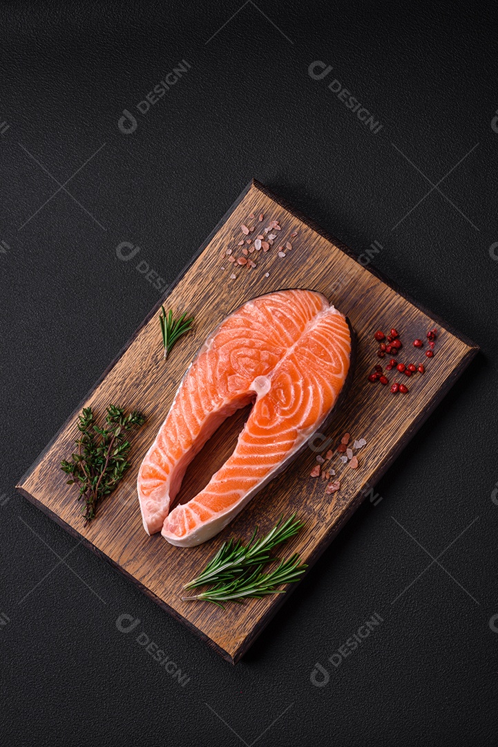 Bife de peixe vermelho cru fresco com especiarias e ervas sobre um fundo escuro de concreto