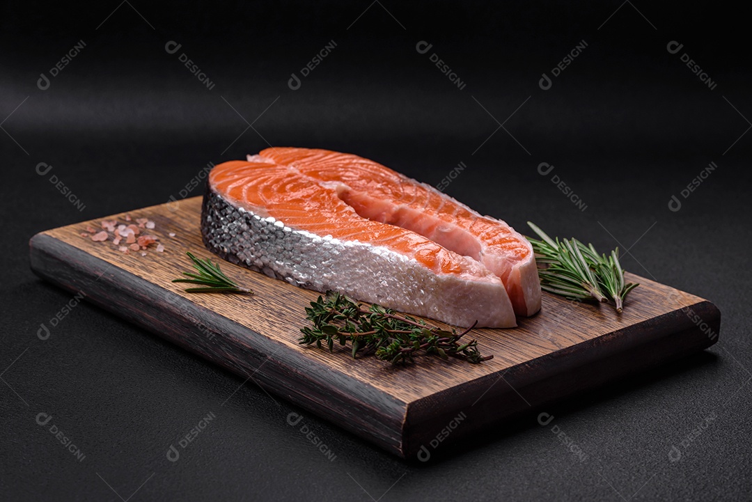 Bife de peixe vermelho cru fresco com especiarias e ervas sobre um fundo escuro de concreto