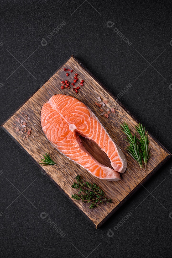 Bife de peixe vermelho cru fresco com especiarias e ervas sobre um fundo escuro de concreto