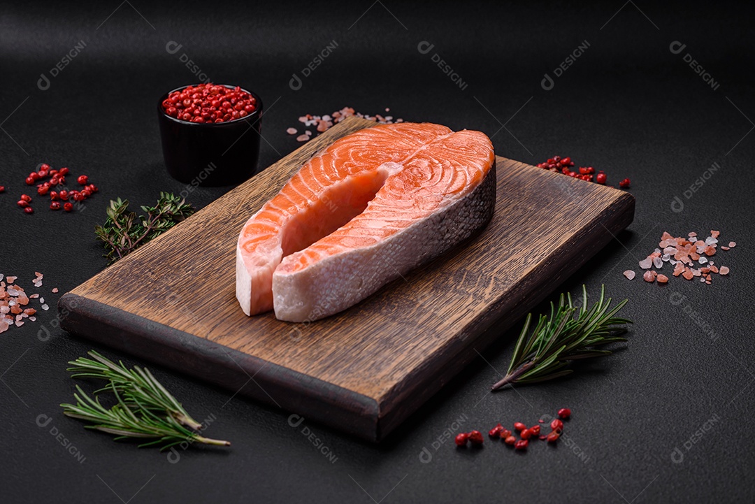 Bife de peixe vermelho cru fresco com especiarias e ervas sobre um fundo escuro de concreto