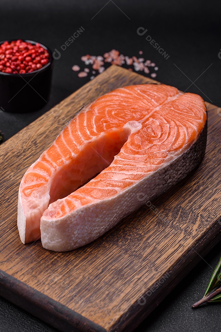 Bife de peixe vermelho cru fresco com especiarias e ervas sobre um fundo escuro de concreto