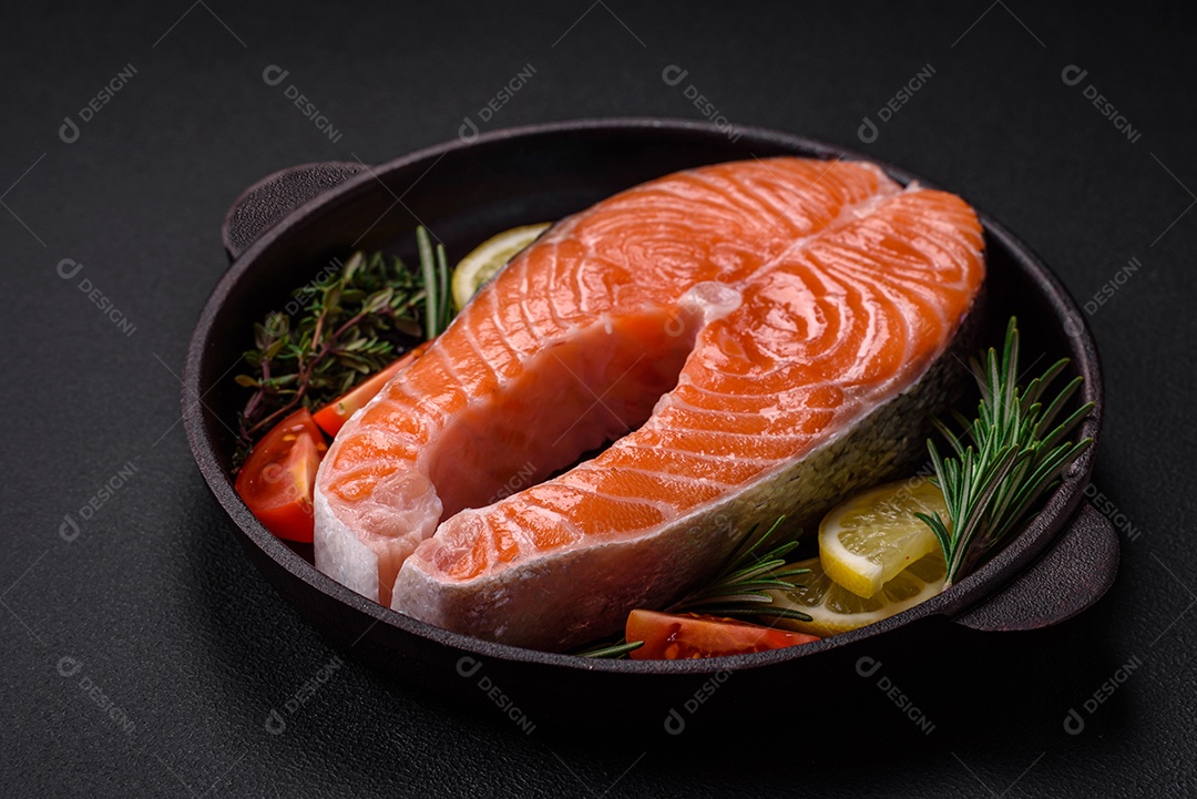 Bife de peixe vermelho cru fresco com especiarias e ervas sobre um fundo escuro de concreto