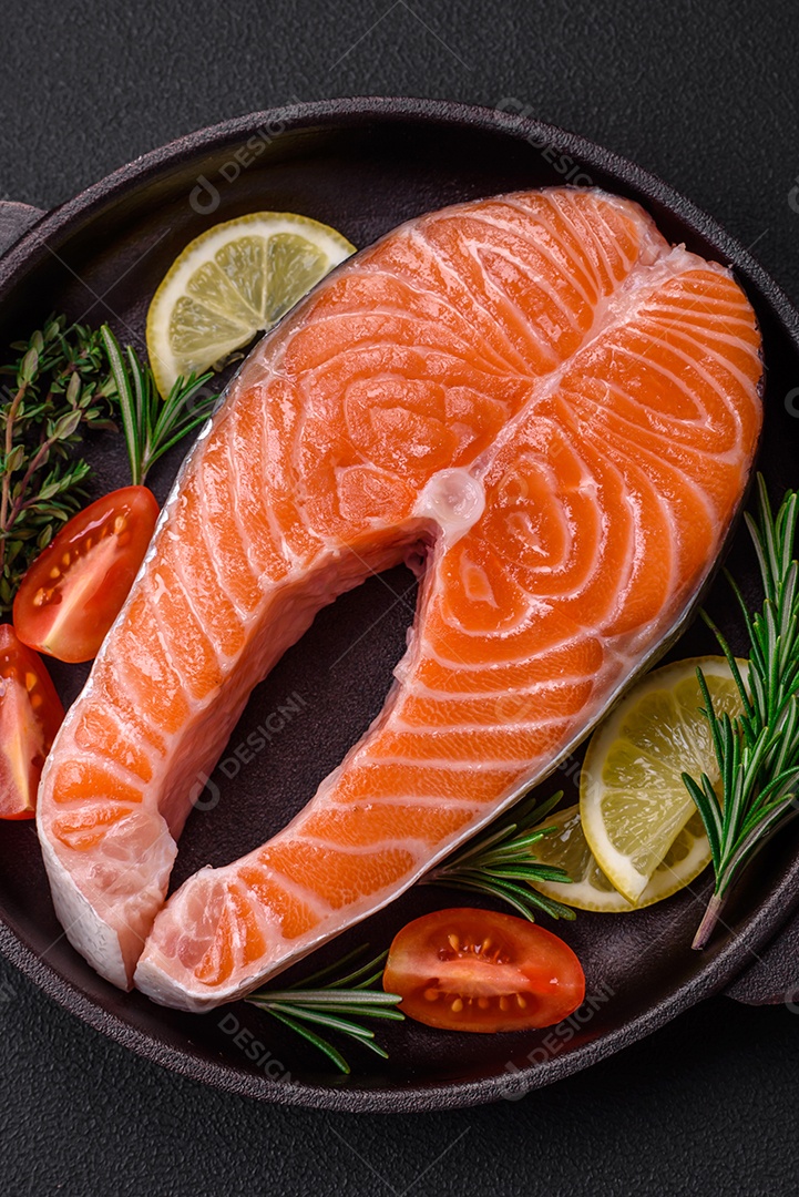 Bife de peixe vermelho cru fresco com especiarias e ervas sobre um fundo escuro de concreto