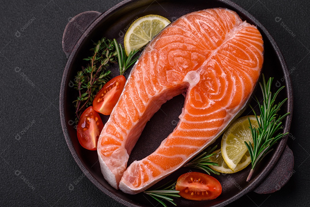 Bife de peixe vermelho cru fresco com especiarias e ervas sobre um fundo escuro de concreto