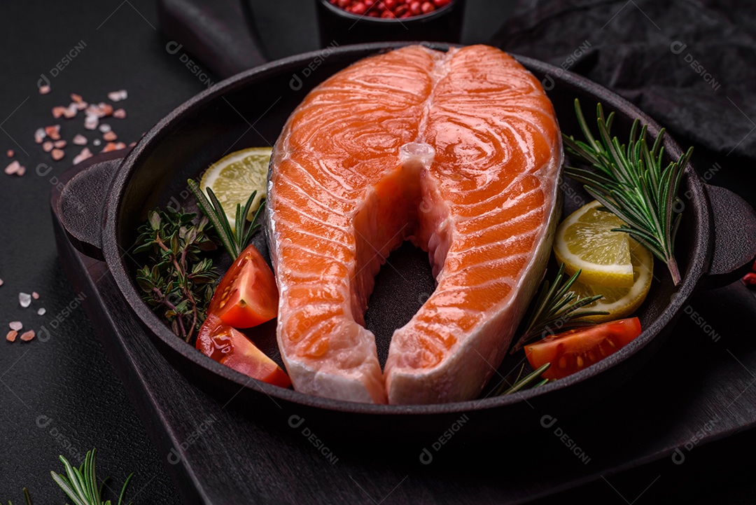 Bife de peixe vermelho cru fresco com especiarias e ervas sobre um fundo escuro de concreto