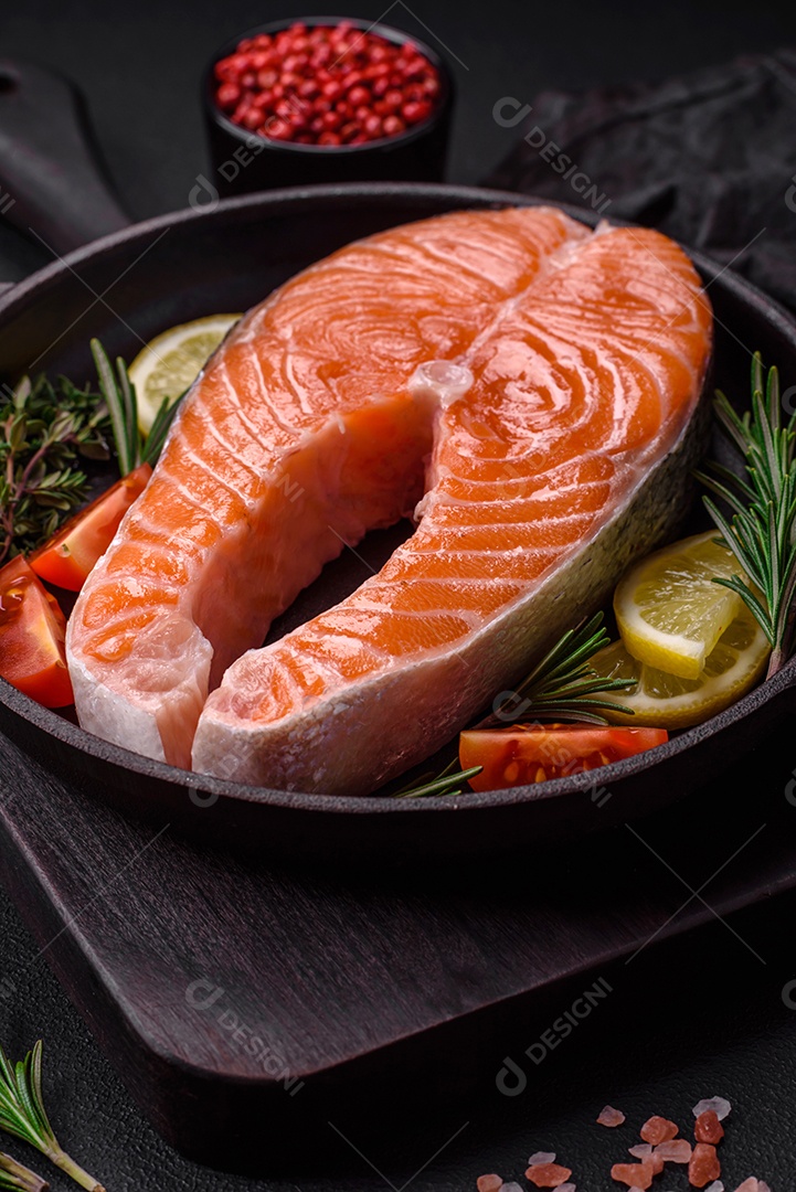 Bife de peixe vermelho cru fresco com especiarias e ervas sobre um fundo escuro de concreto