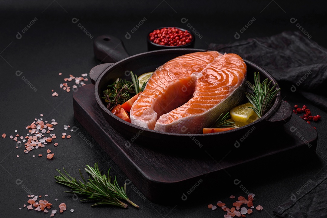 Bife de peixe vermelho cru fresco com especiarias e ervas sobre um fundo escuro de concreto