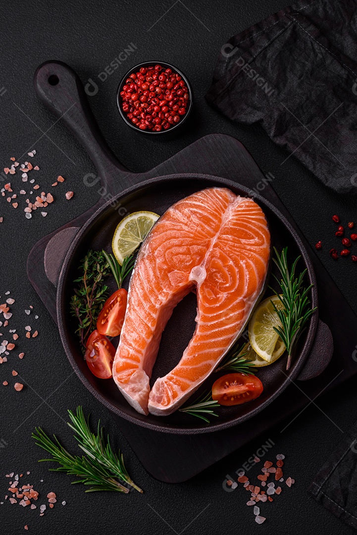 Bife de peixe vermelho cru fresco com especiarias e ervas sobre um fundo escuro de concreto