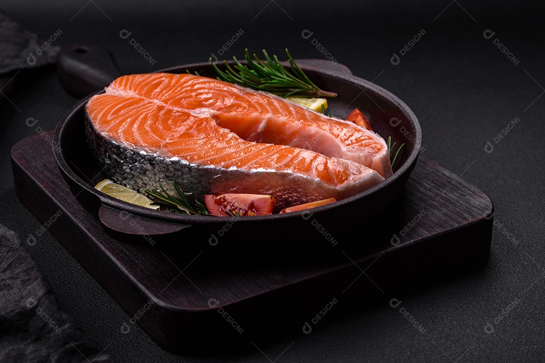 Bife de peixe vermelho cru fresco com especiarias e ervas sobre um fundo escuro de concreto