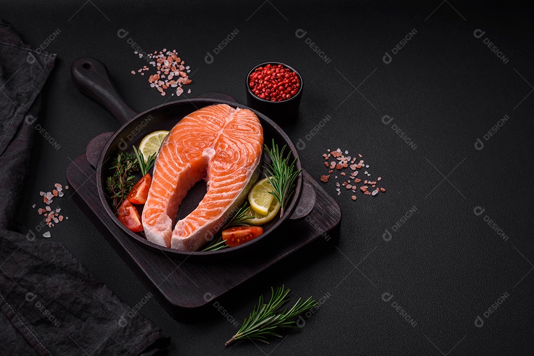 Bife de peixe vermelho cru fresco com especiarias e ervas sobre um fundo escuro de concreto