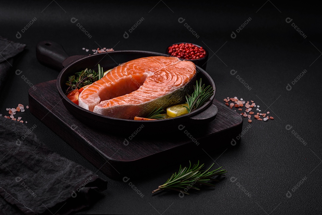 Bife de peixe vermelho cru fresco com especiarias e ervas sobre um fundo escuro de concreto