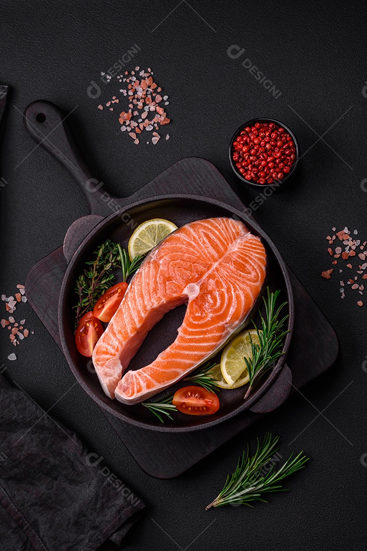 Bife de peixe vermelho cru fresco com especiarias e ervas sobre um fundo escuro de concreto